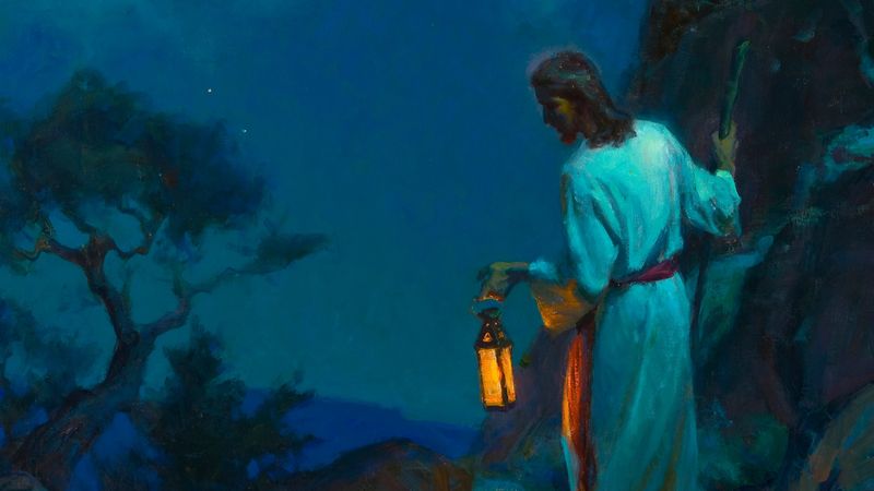 A night scene in deep blue: Jesus Christ in a pale robe with a crimson sash, walking a dark hillside path among olive trees, holding out a lit lantern whose warm golden light is the only brightness in the picture.