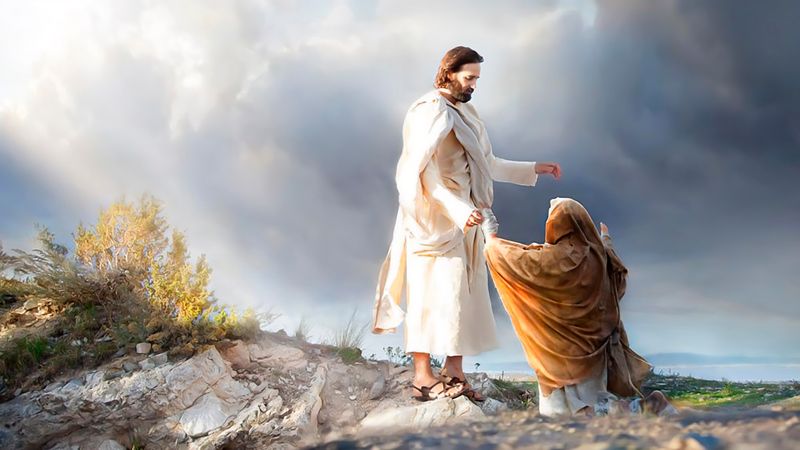 On a rocky hillside under a bright, broken sky, Jesus Christ in white robes reaches down and takes the hand of a woman kneeling before him in a brown cloak, lifting her to her feet as sunlight breaks through the clouds behind them.
